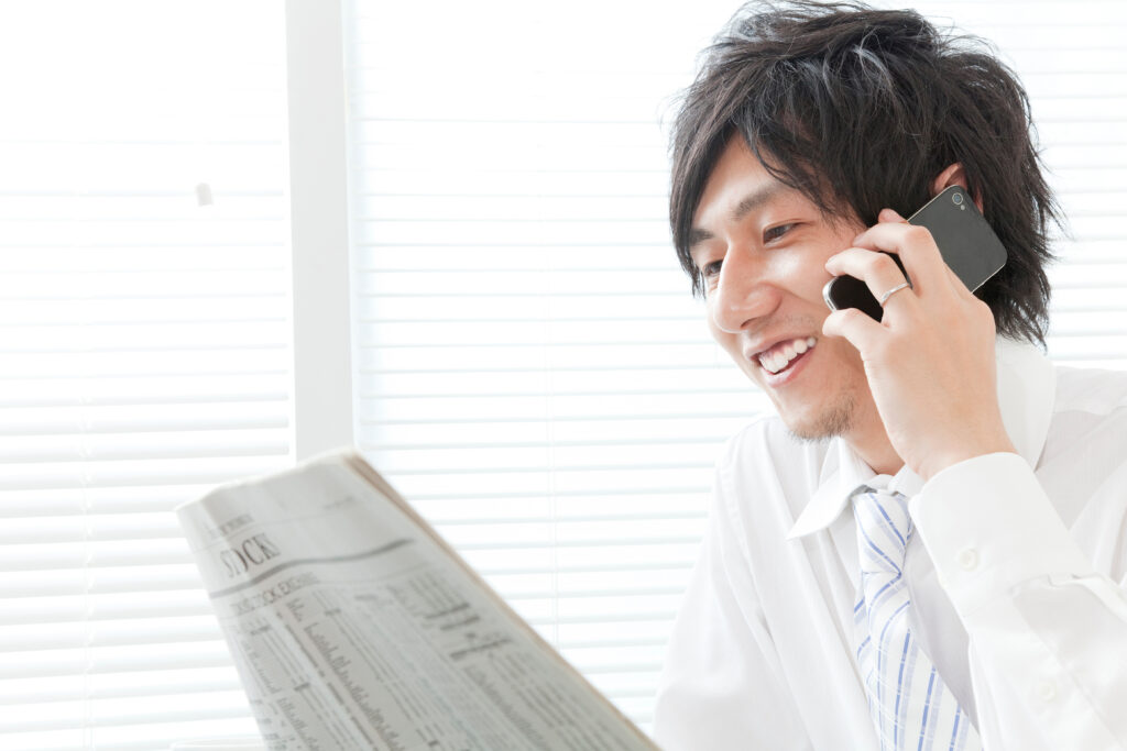 書類を前に携帯電話で話す笑顔の男性