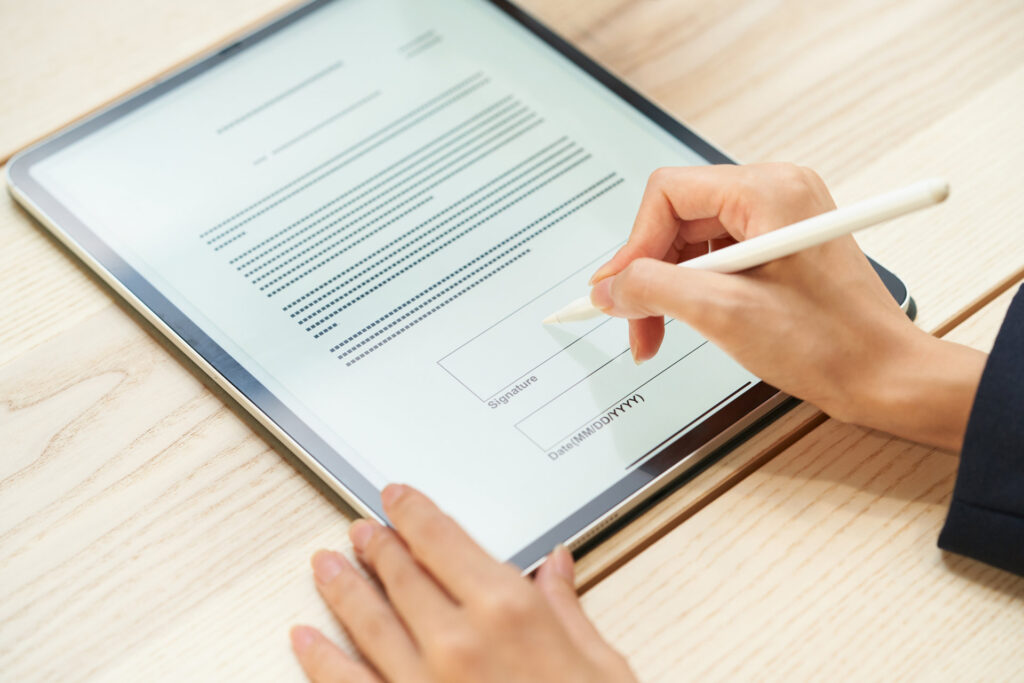 タブレットの書類に電子ペンで署名する手元