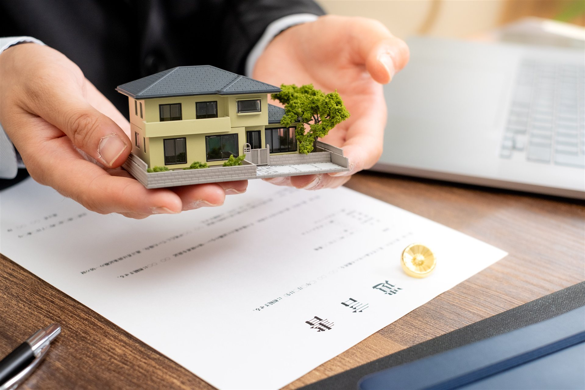住宅の模型を両手で持つ手元と書類