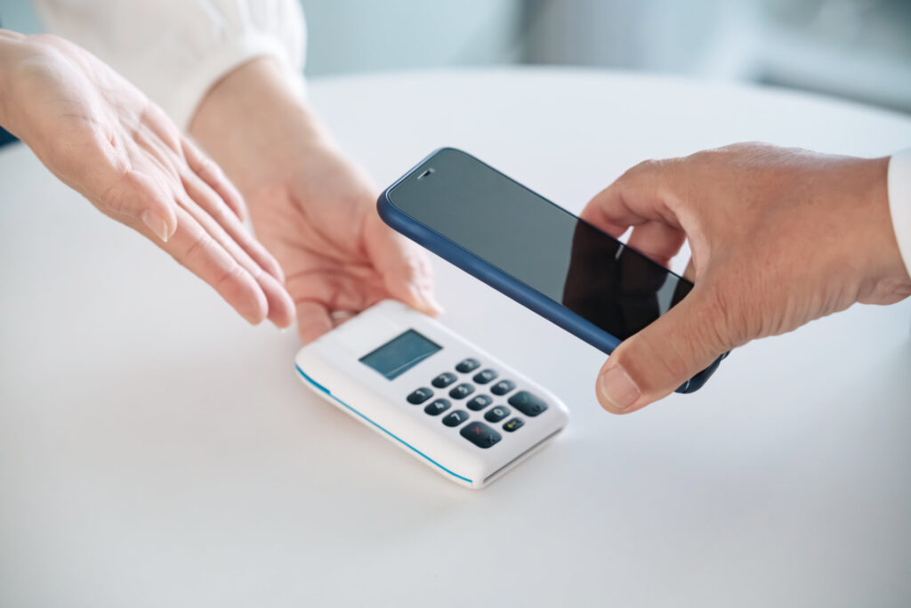 スマートフォンを決済の端末にかざして支払う手元