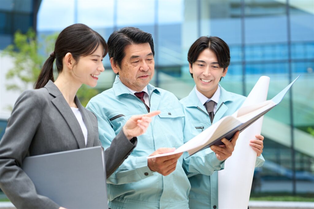 書類を広げて話し合う会社員と作業着の人たち