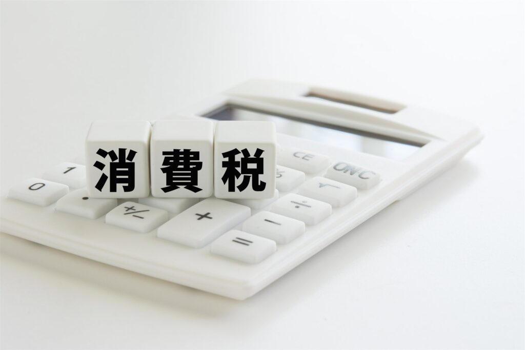 電卓の上に置いた「消費税」の文字の積み木