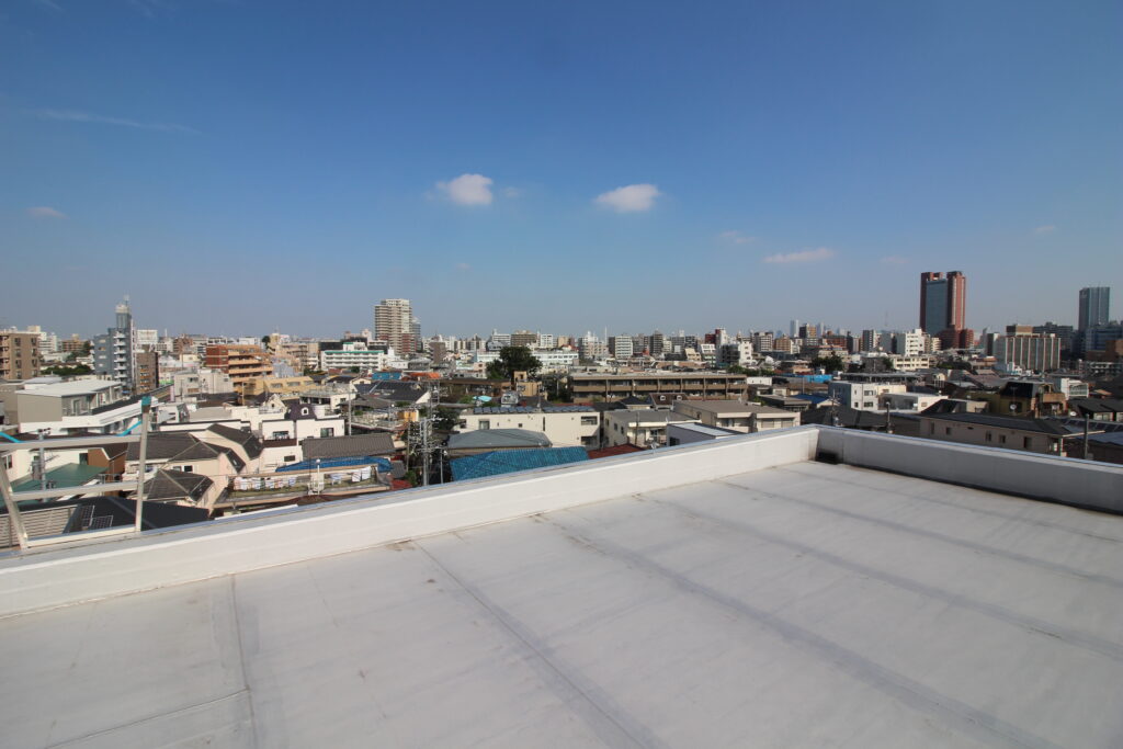 防水を仕上げた屋上と向こうに広がる住宅街