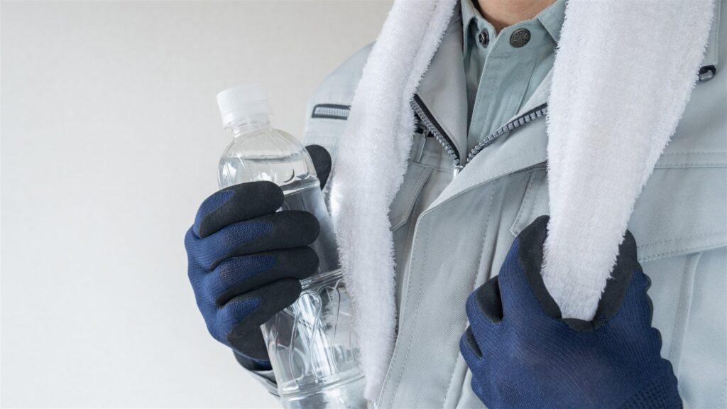 水のボトルとタオルを持つ作業着の人