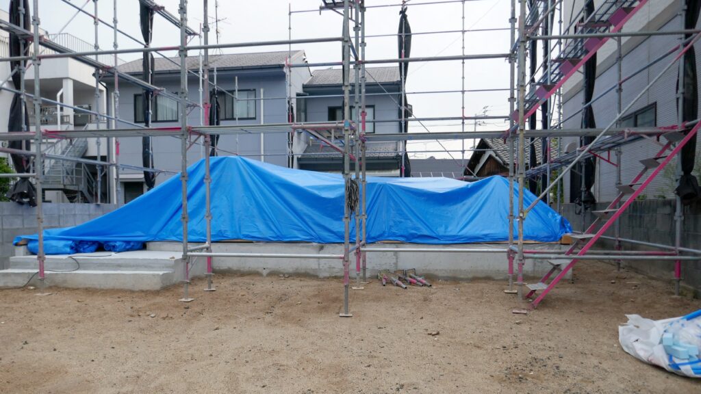 足場を組みブルーシートで覆った住宅の基礎
