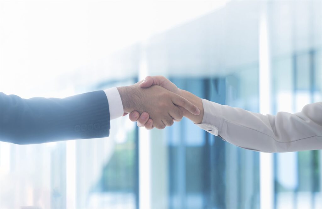 窓辺で握手をするスーツ姿の2人の手元