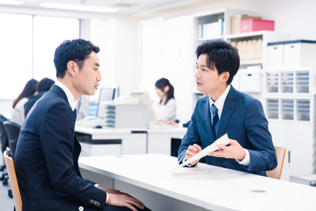 事務所の窓口で書類を前に相談する2人