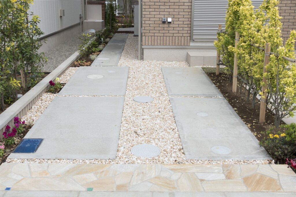 石を敷いた戸建て住宅の駐車場と植栽の外構
