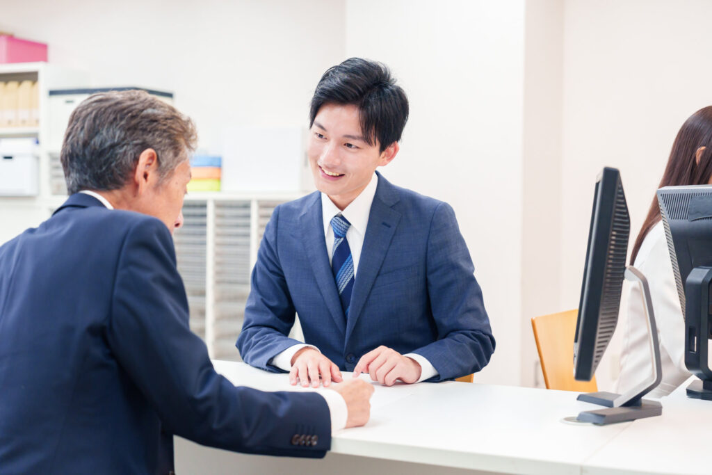 窓口で担当者に書類の内容を相談する男性