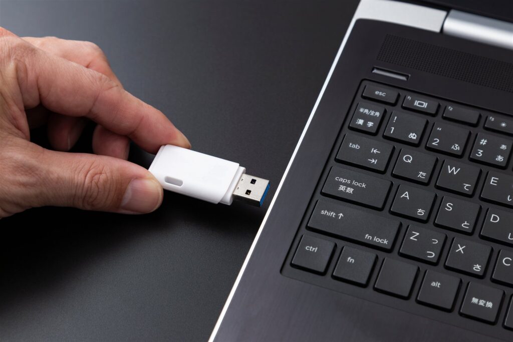 ノートパソコンに USB メモリを差し込む手元