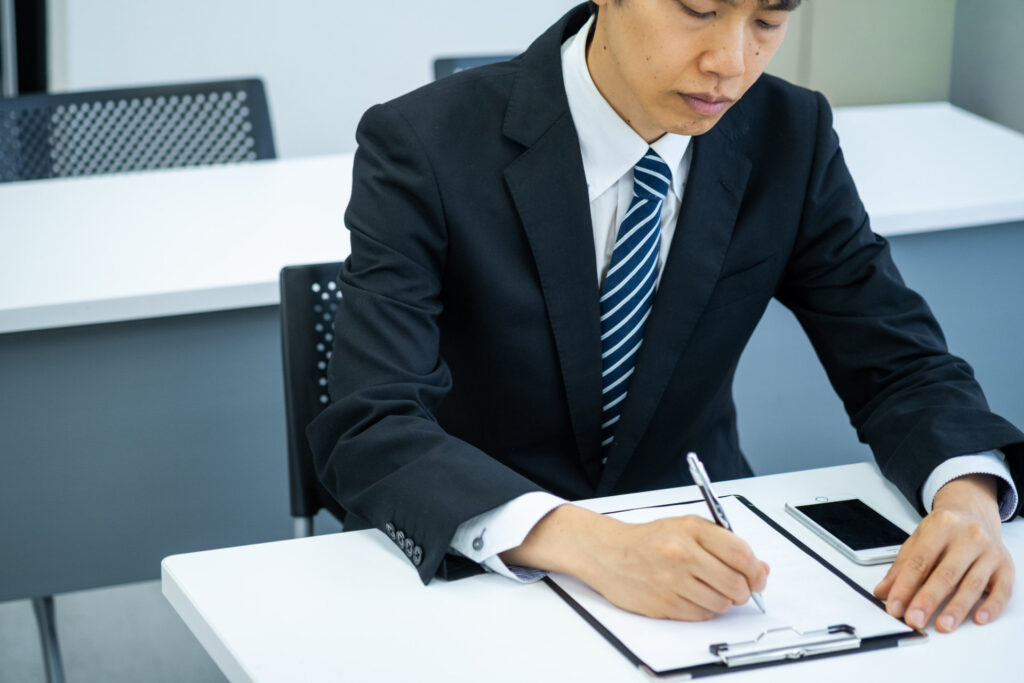 スーツの男性がクリップボードに記入する
