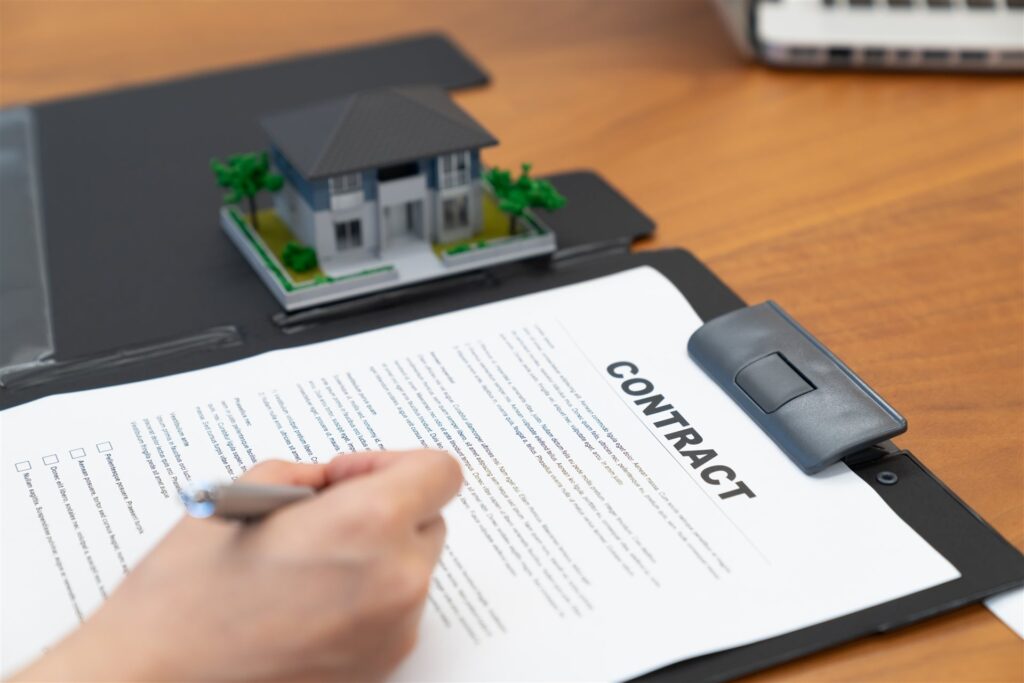 住宅の模型のそばで契約書に記入する手元