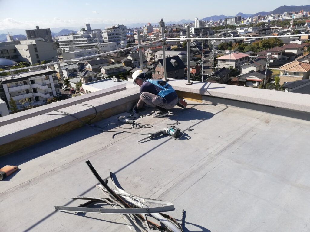 晴れた日に建物の屋上で改修の作業をする職人