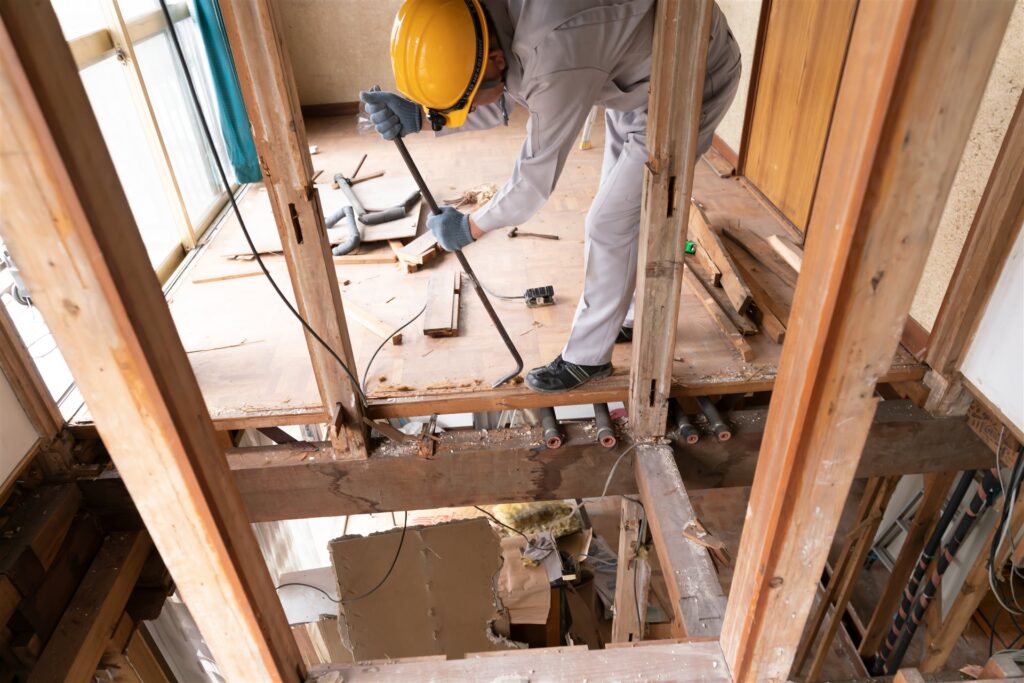 木造住宅の床板をバールで外す作業員