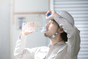 作業着でペットボトルの水を飲む男性