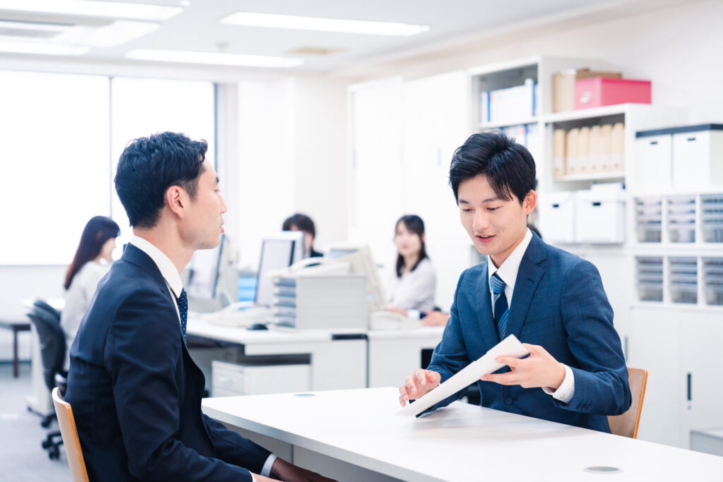 事務所の窓口で男性が書類を見せて説明する様子