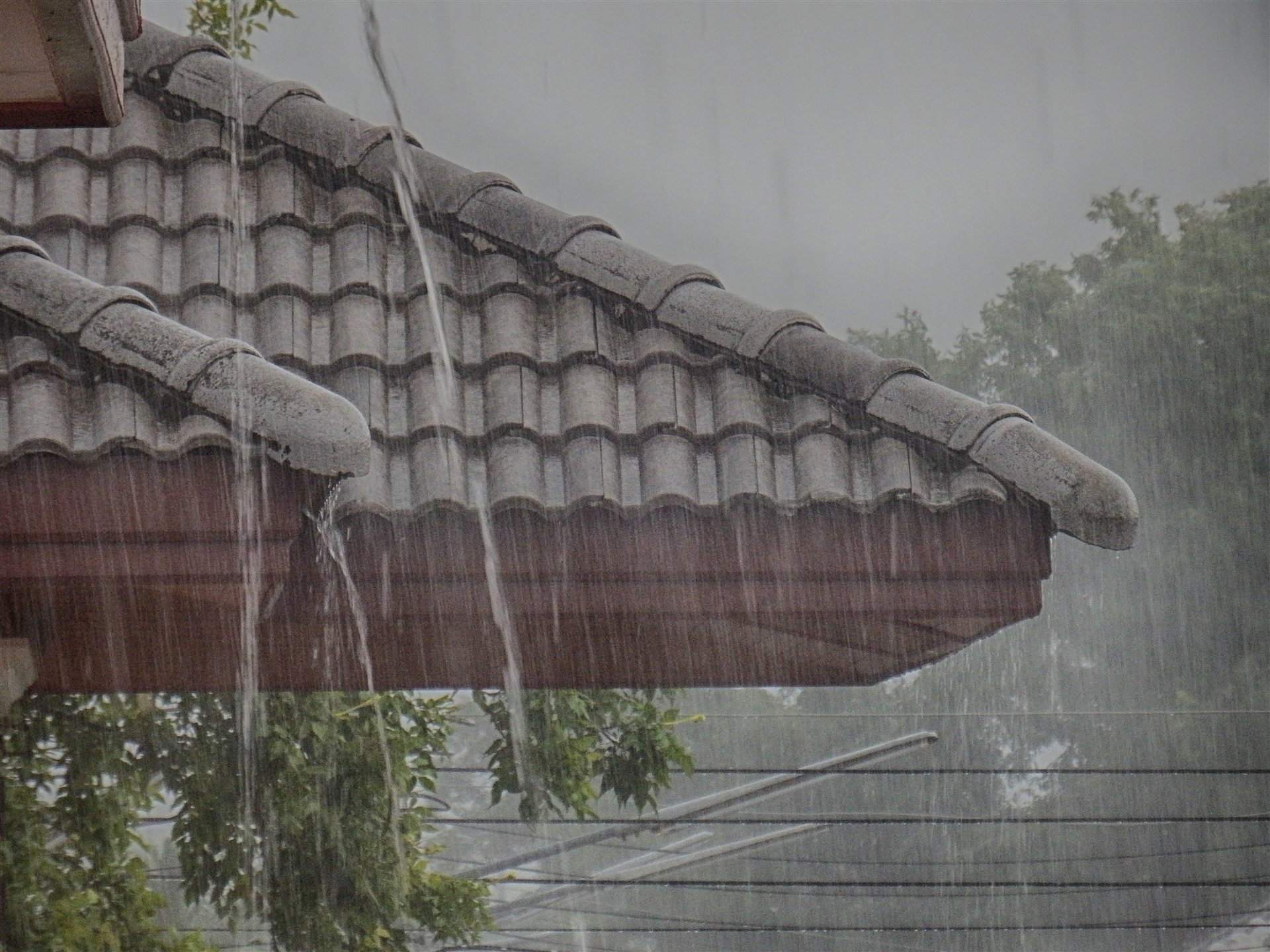 瓦屋根から流れ落ちる大雨