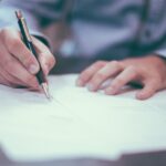 書類にサインするビジネスパーソン（業種追加申請イメージ）