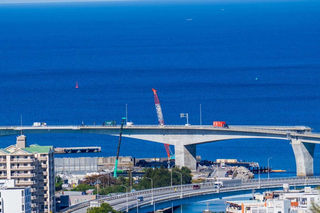 Aerial view of a coastal bridge under construction over a deep blue sea.