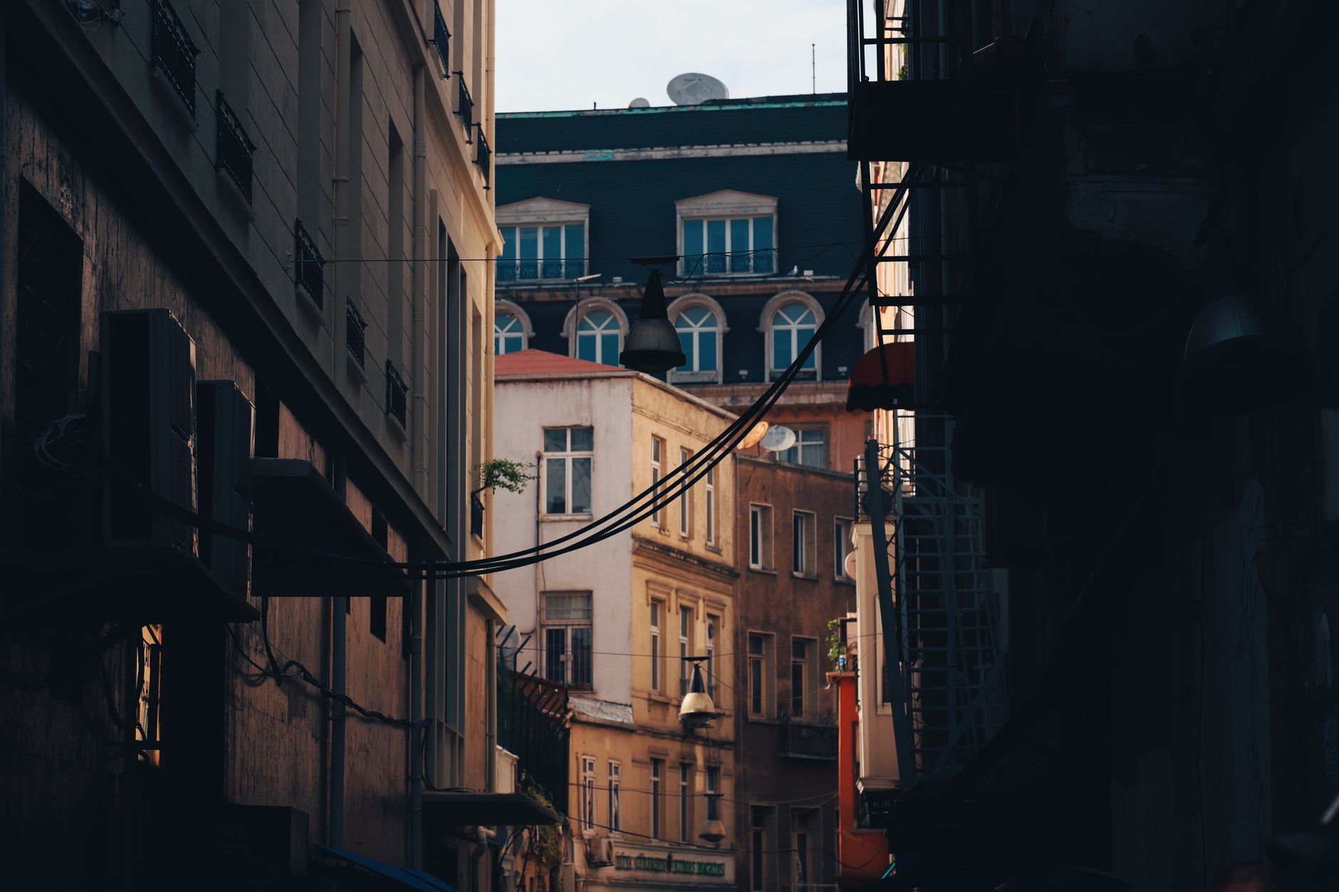 Narrow city alleyway with historic buildings and overhead cables, conveying urban charm and connectivity.