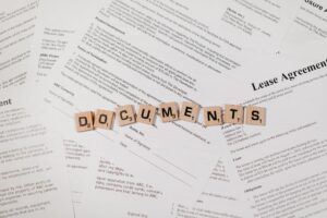 Top view of scrabble tiles spelling DOCUMENTS on various contracts and agreements.