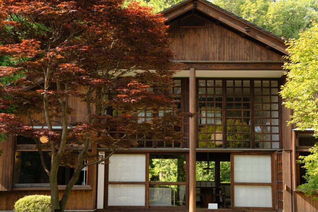 紅葉の木に囲まれた木造の家