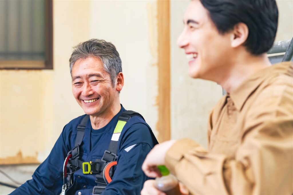 現場で笑顔で話すベテランの職人と若い職人