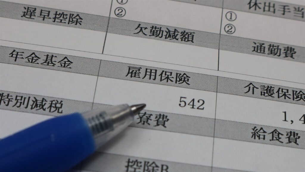 雇用保険・社会保険の欄がある給料明細とペン