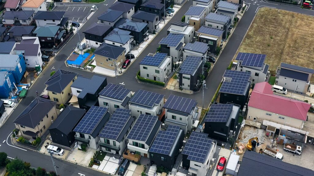 屋根に太陽光パネルを載せた住宅が並ぶ住宅地の空撮