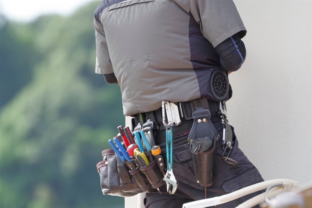 腰に工具を付けた空調服の作業員の後ろ姿