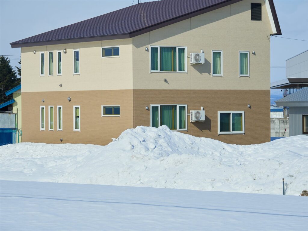 雪の積もった前庭のある2階建ての家