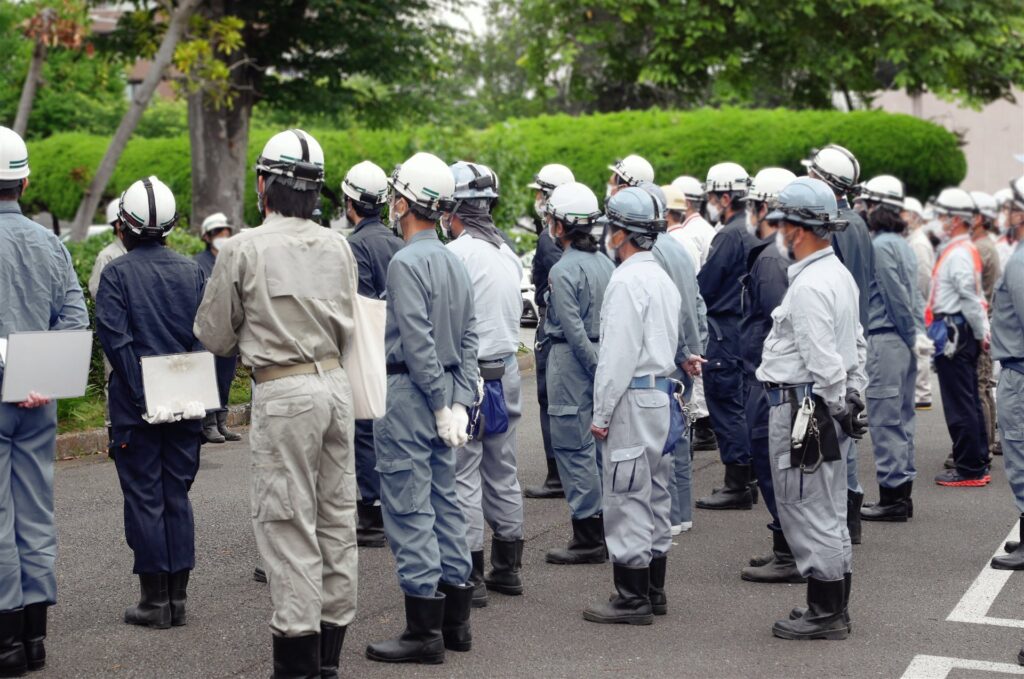 ヘルメットと作業服の大勢が並ぶ朝礼の後ろ姿