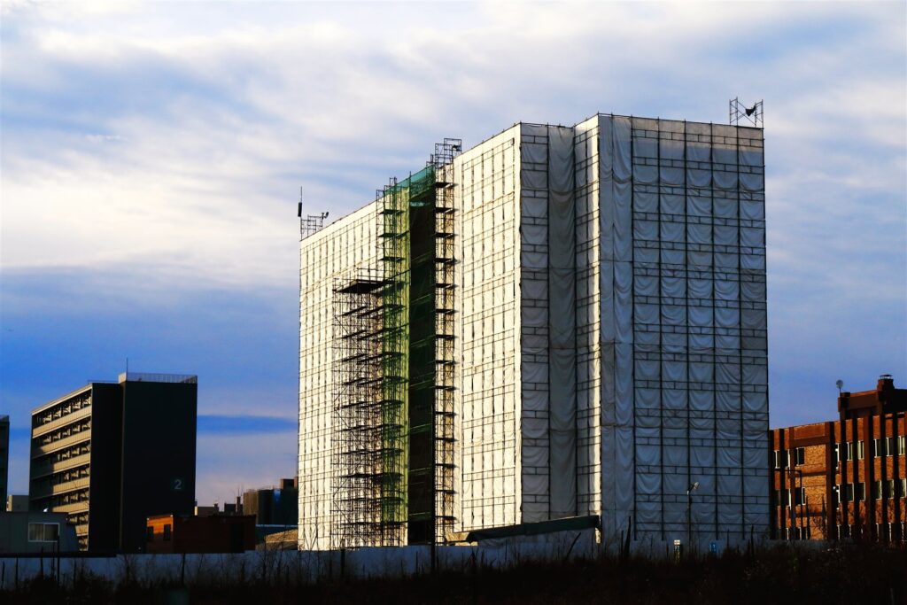 足場とシートに覆われた建設中の高い建物