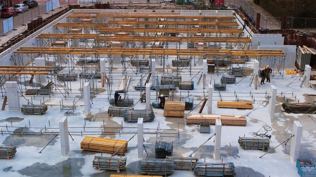 A busy construction site with scaffolding, steel structures, and workers.