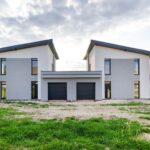 Front view of twin modern houses with a symmetrical architectural design under a cloudy sky.