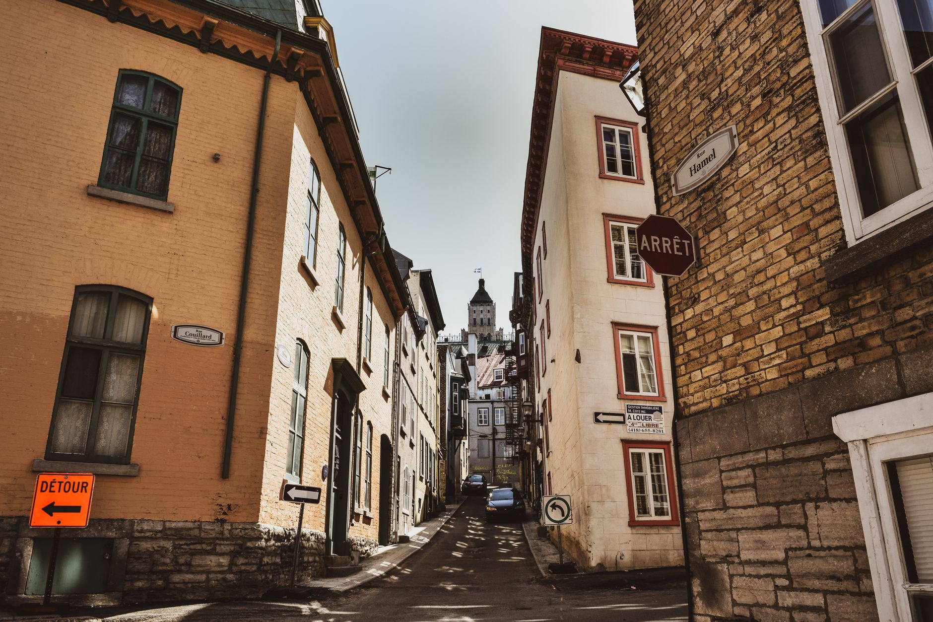 Quaint alleyway in Quebec City with historic architecture under a clear sky.