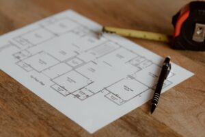 Architecture scheme of floor on paper placed on wooden surface near pen and ruler in room during renovation work in building