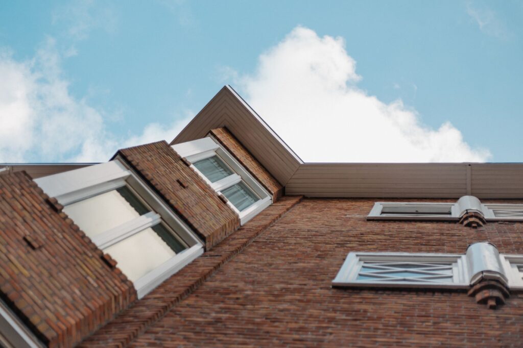 Low angle shot of a brick building with glass windows against a clear blue sky.