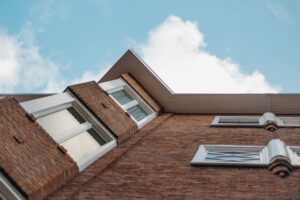 Low angle shot of a brick building with glass windows against a clear blue sky.