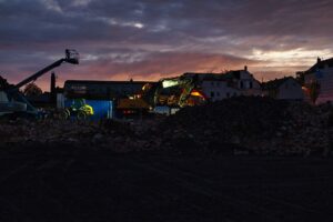 Excavation site with construction equipment during twilight, showcasing a dramatic sky.