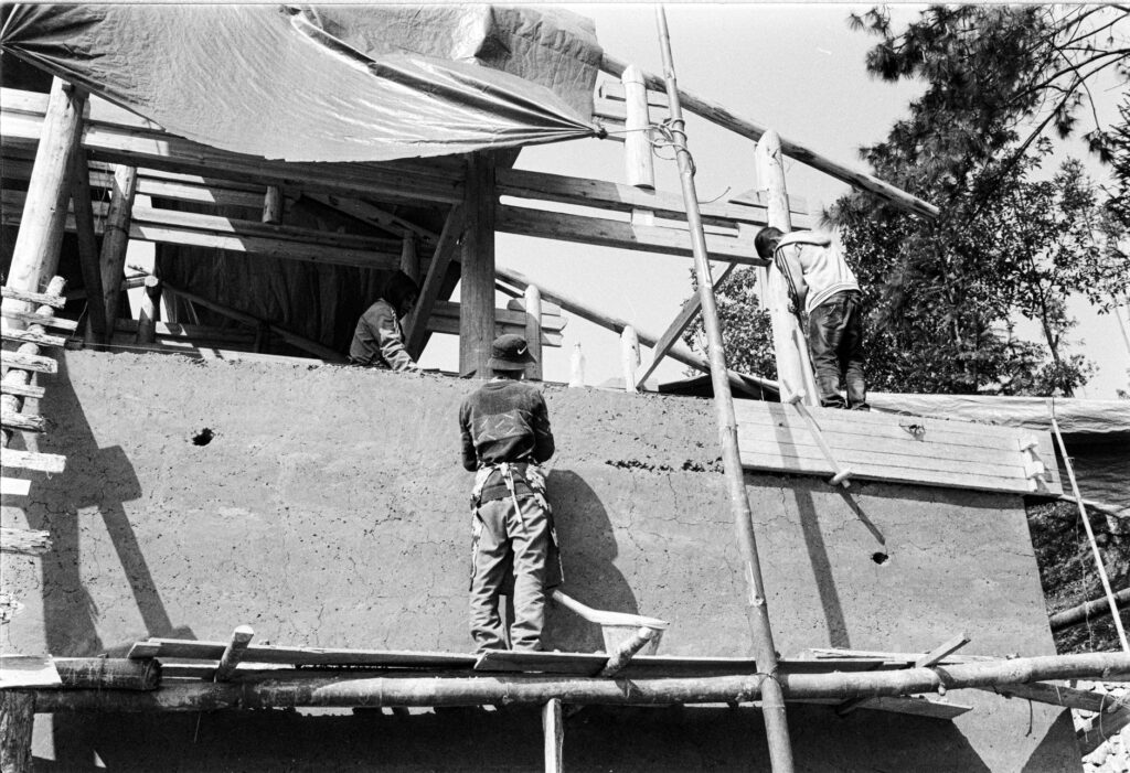 Monochrome image of workers at a construction site with scaffolding.
