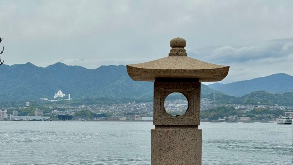海辺に立つ石灯籠と対岸の町並み