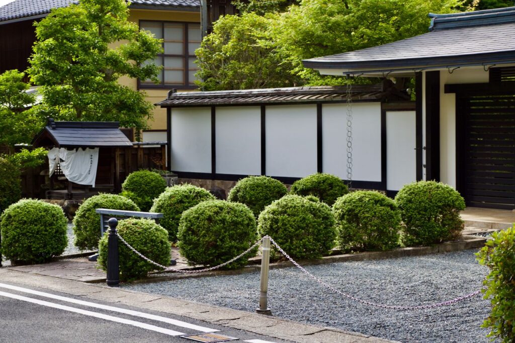 刈り込んだ植木が並ぶ日本庭園と家