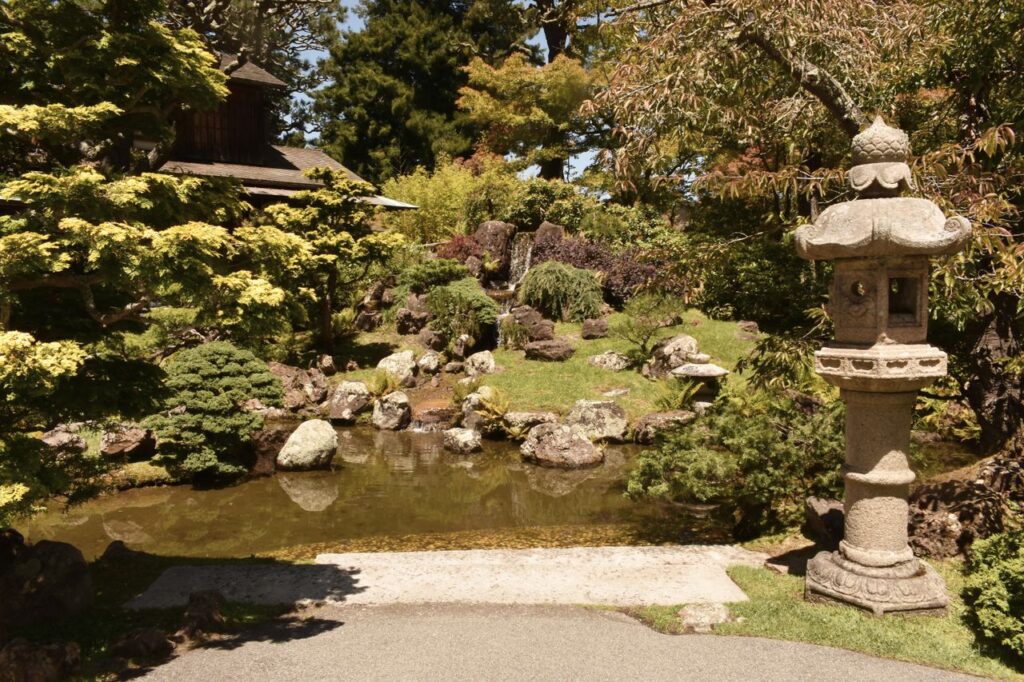 池と滝のある庭に立つ石灯籠