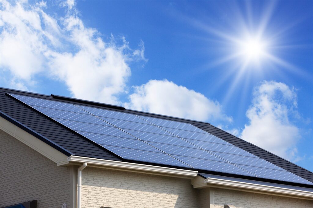 住宅の屋根に並ぶ太陽光パネルと青空