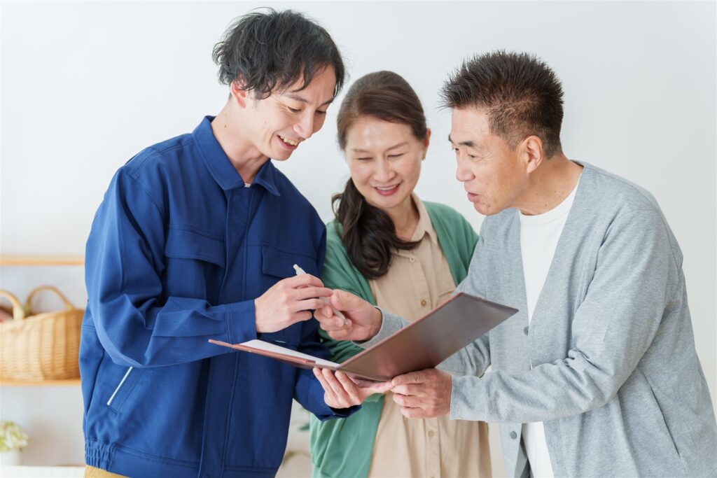 作業着の男性と契約書を確かめる夫婦