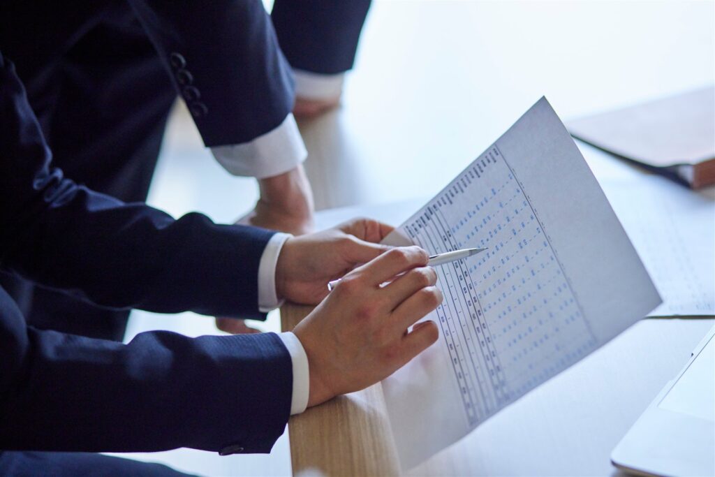 スーツの人がペンで表の書類を確かめる手元