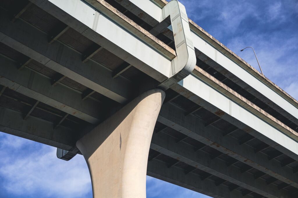 Upward angle shot of a sturdy concrete bridge against a vibrant blue sky.