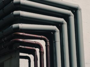 Close-up of industrial pipes forming a pattern on a buildings exterior wall, shot outdoors.