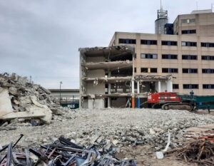 Urban building partially demolished with rubble and machinery.